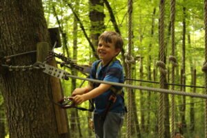 Un enfant sur un parcours d'accrobranche qui est très heureux